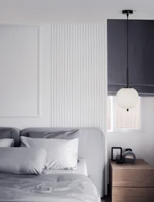 A bedroom scene with a bed and a pendant lamp.