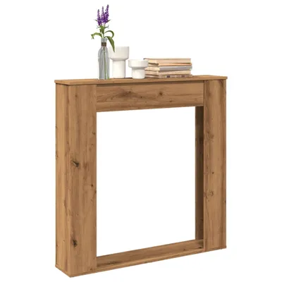 A wooden surround for a fireplace, decorated with a vase of flowers and books.