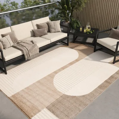 An outdoor patio setting with modern furniture and a rug.
