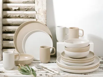 A collection of stoneware plates and mugs arranged on a rustic wooden surface.