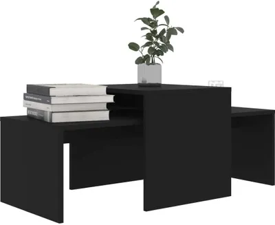 A set of black nesting coffee tables with books stacked on one and a plant on the other.