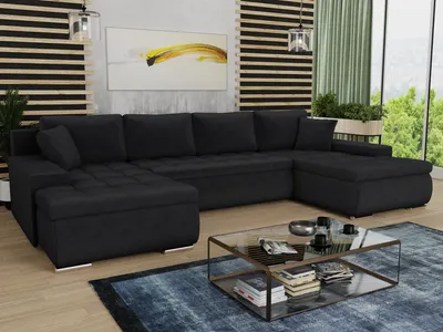 A modern living room with a large U-shaped black sofa, a glass coffee table, and a painting on the wall.