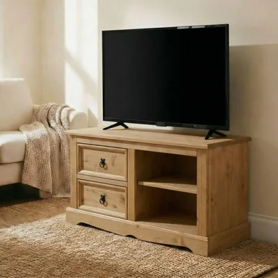 A TV stand with a TV on top, placed in a living room setting with a sofa and blanket.