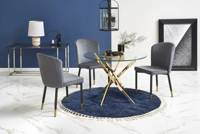 A dining set with a round glass table and four chairs, placed on a blue rug.