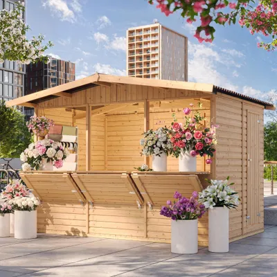A wooden garden bar/sales booth is set up outdoors, decorated with various flower arrangements in pots. Buildings and trees are visible in the background under a blue sky with clouds.