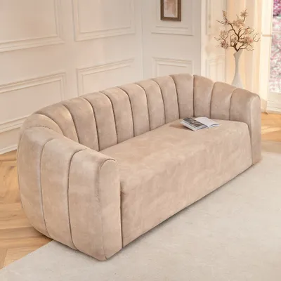 A beige velvet sofa with channel tufting in a well-lit room.