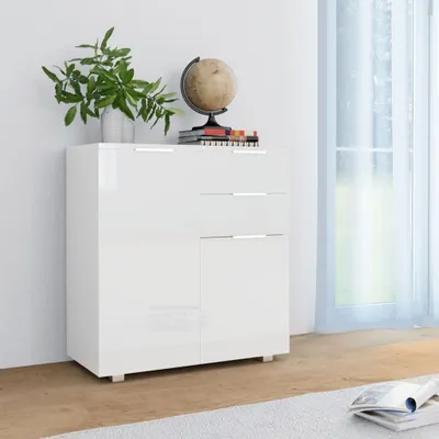 A white sideboard with drawers and doors, decorated with a plant and a globe on top, placed in a room with a window and sheer curtains.