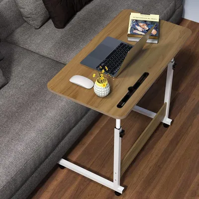 A laptop table is placed next to a sofa, with a laptop, mouse, and a book on it.