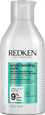 A white bottle of Redken shampoo with green and teal accents on the label.