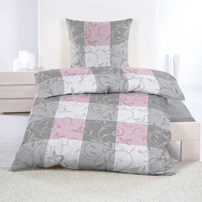 A neatly made bed with seersucker bedding in a gray, pink, and white checkered pattern.