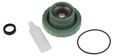 A set of washing machine parts, including a green cap with internal metal components, a small white tube of lubricant, and two black rubber rings, laid out on a white background.