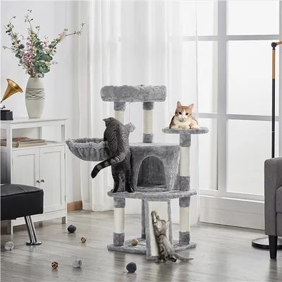 A multi-level cat tree with two cats interacting with it, placed in a living room setting with furniture and decor.