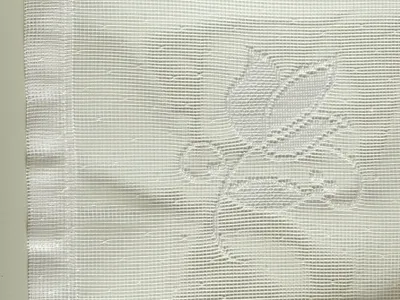 A close-up of white fabric with a subtle embossed floral pattern.