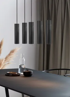 A dining table with a modern pendant light fixture above it.
