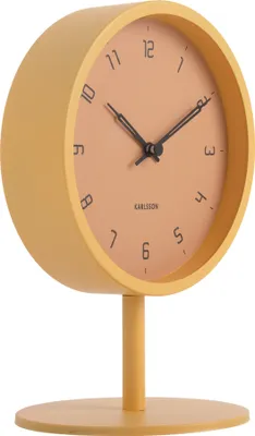 A yellow desk clock with a peach-colored face and black hands, shown on a white background.