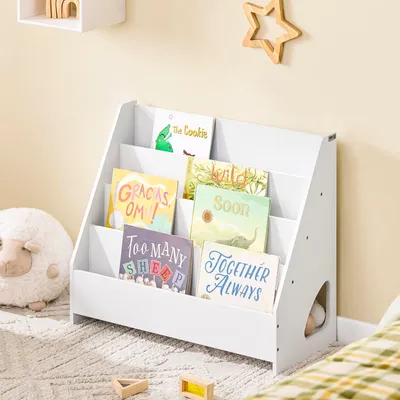 A white children's bookshelf filled with colorful books, placed in a child's room with a stuffed sheep toy and wooden blocks.