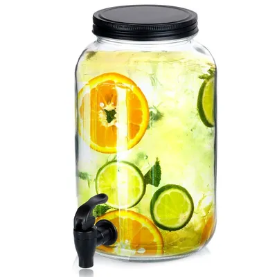 A glass beverage dispenser filled with water, ice, and slices of orange and lime.