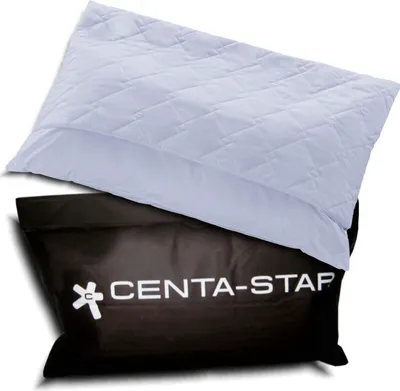 A white quilted pillow is placed on top of a black bag with white text and a logo.