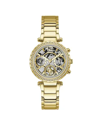 A gold-colored Guess women's watch with a skeleton dial and crystal embellishments on the bezel, presented on a white background.