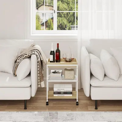 A rolling cart with books and bottles of wine sits between two white sofas in a living room.