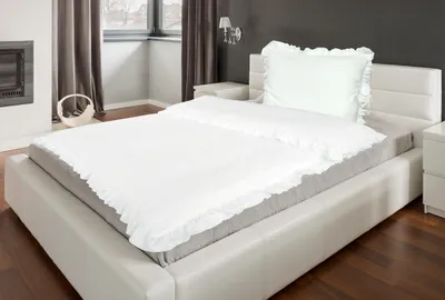 A neatly made bed with white bedding and a pillow in a bedroom setting.