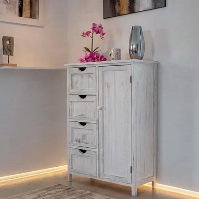 A white distressed cabinet with drawers and a door, decorated with a pink orchid and a silver vase.