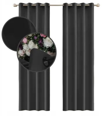 A close-up view of a dark gray velvet curtain with a grommet opening, showing a bouquet of flowers through the opening.