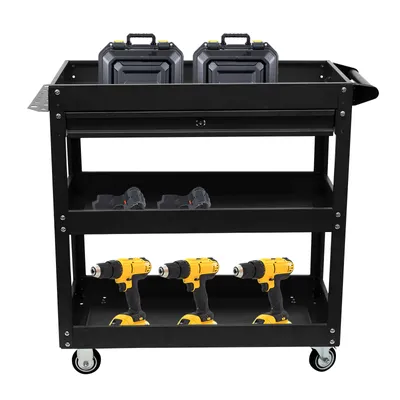 A black rolling tool cart with three shelves, containing two tool cases on the top shelf, two battery packs on the middle shelf, and three yellow power drills on the bottom shelf.
