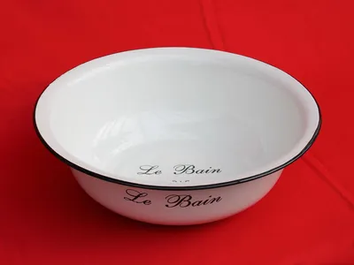 A white enamel basin with black trim sits on a red surface.
