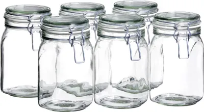 A group of six clear glass jars with silver wire bail closures and green lids are arranged on a white background.