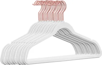 A stack of white velvet hangers with rose gold hooks against a white background.