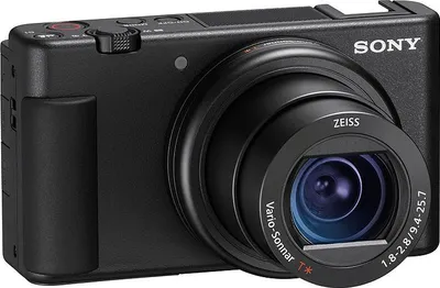 A black Sony ZV-1 digital camera is shown from a front-side angle against a white background.