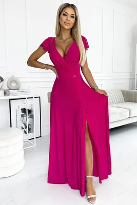A woman models a fuchsia maxi dress in a well-lit room with modern decor.