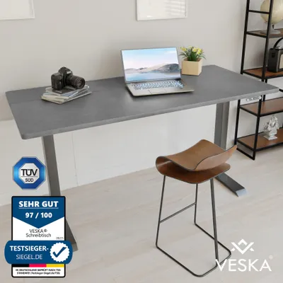 A modern office setup with an adjustable desk and a stool.