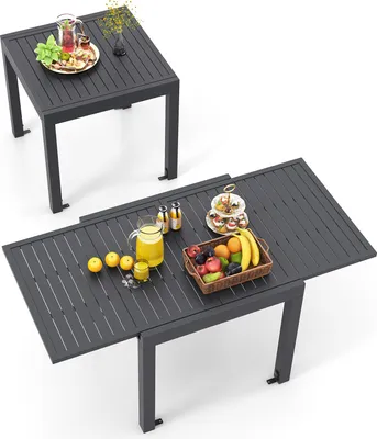 Two outdoor tables, one extended, with fruit and drinks on them.