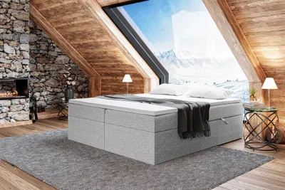 A cozy bedroom with a large window overlooking a snowy mountain landscape.