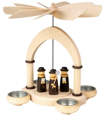 Romantische Säulenpyramide aus natur- und dunkelbraun gefärbtem Holz mit geschwungener Bogenkonstruktion, drei Weihnachtssängerfiguren in der Mitte und drei Teelichthaltern. Erzgebirgskunst mit drehbarem Flügelrad.