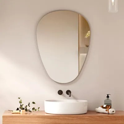 A modern bathroom vanity with a sink, faucet, and an asymmetrical mirror above it.
