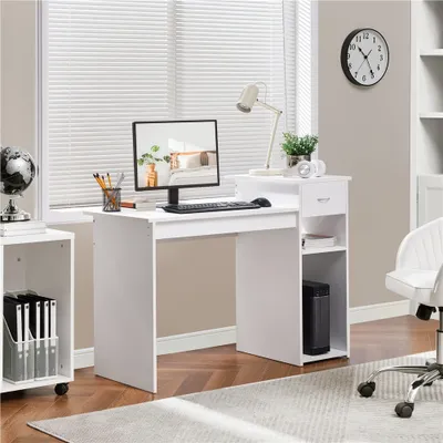 A white computer desk with a monitor, keyboard, lamp, and storage shelves is set up in a room with blinds and a clock on the wall.