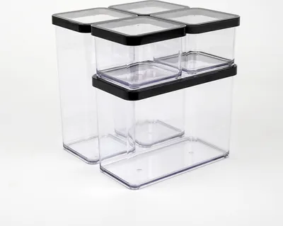 A set of five clear plastic food storage containers with black lids, stacked and arranged on a white background.