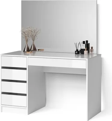 A white vanity table with drawers and a large mirror, decorated with vases of dried flowers and perfume bottles.