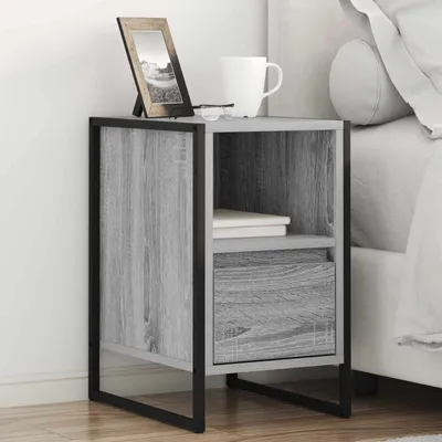 A bedside table with a picture frame, glasses, and a mug on it, placed next to a bed.
