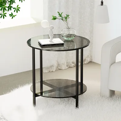 A round glass-top side table with a metal frame and a lower shelf, placed on a fluffy white rug next to a white armchair. A small white figurine and a vase with greenery are on the table.