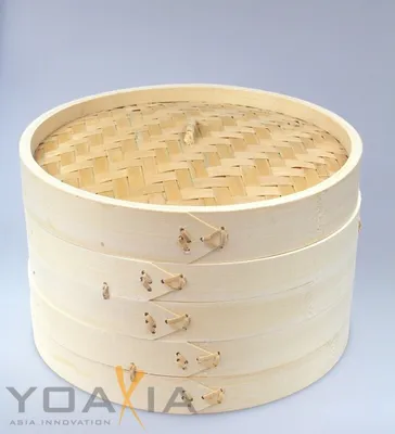 A stack of three bamboo steamer baskets with a woven bamboo lid, set against a plain light gray background.