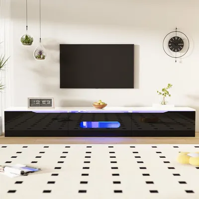 A modern living room setup featuring a black and white TV stand with LED lighting, a wall-mounted TV, and decorative hanging plants.
