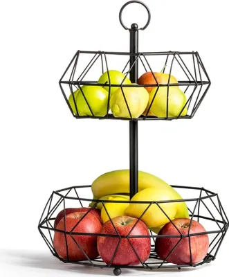 A two-tiered black metal fruit basket filled with apples, lemons, and bananas, set against a white background.