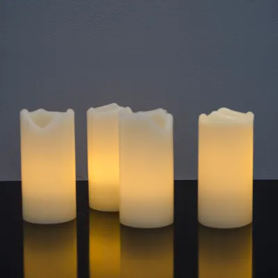 Four LED candles are arranged on a reflective black surface against a dark gray background.