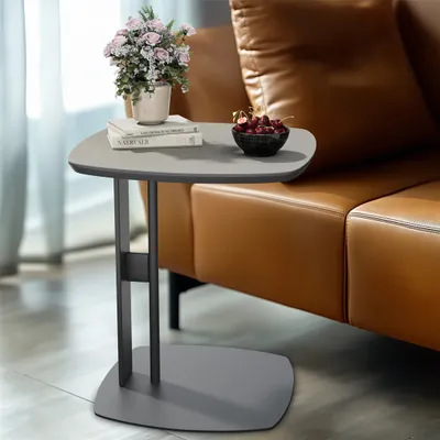A side table with books, flowers, and cherries next to a leather sofa.
