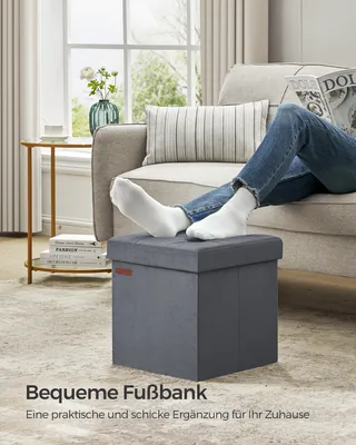 A person is relaxing on a couch with their feet on a footstool, reading a magazine.