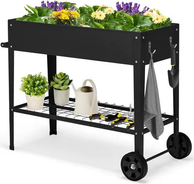 A black metal raised garden bed with plants and gardening tools.